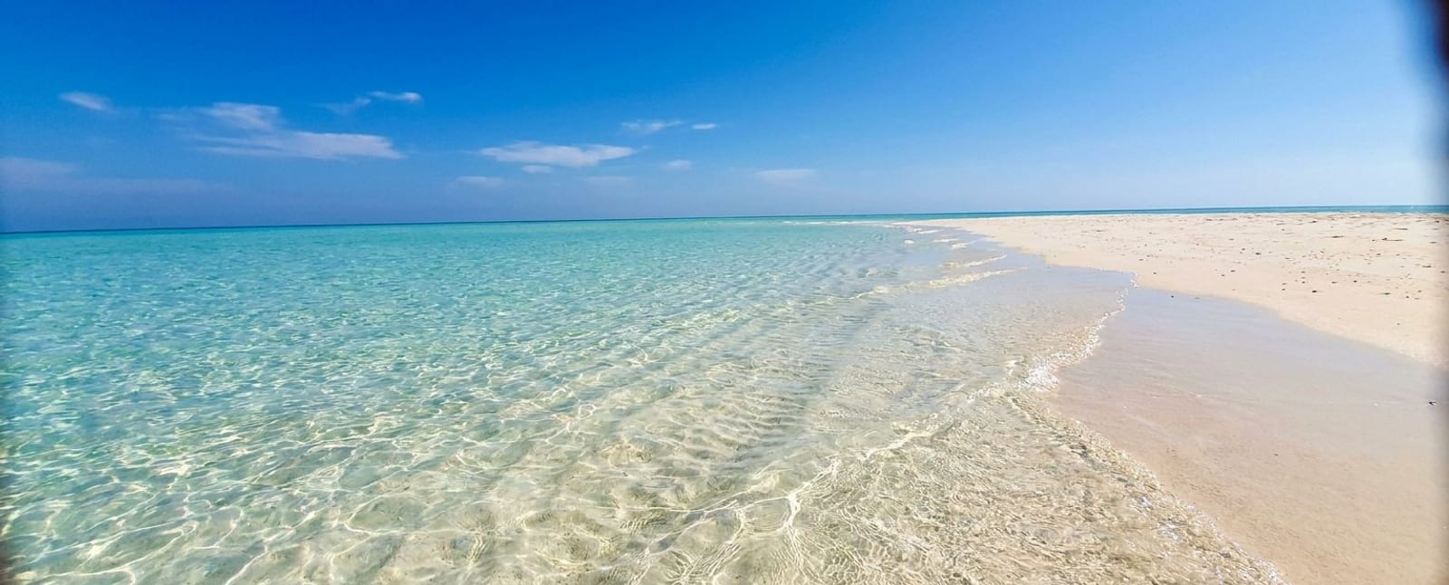 Shallow clear water running up pale sand.